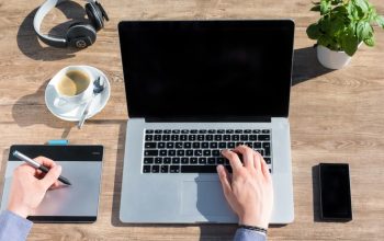 A stylish home office workspace featuring a laptop, drawing tablet, and coffee on a wooden desk.